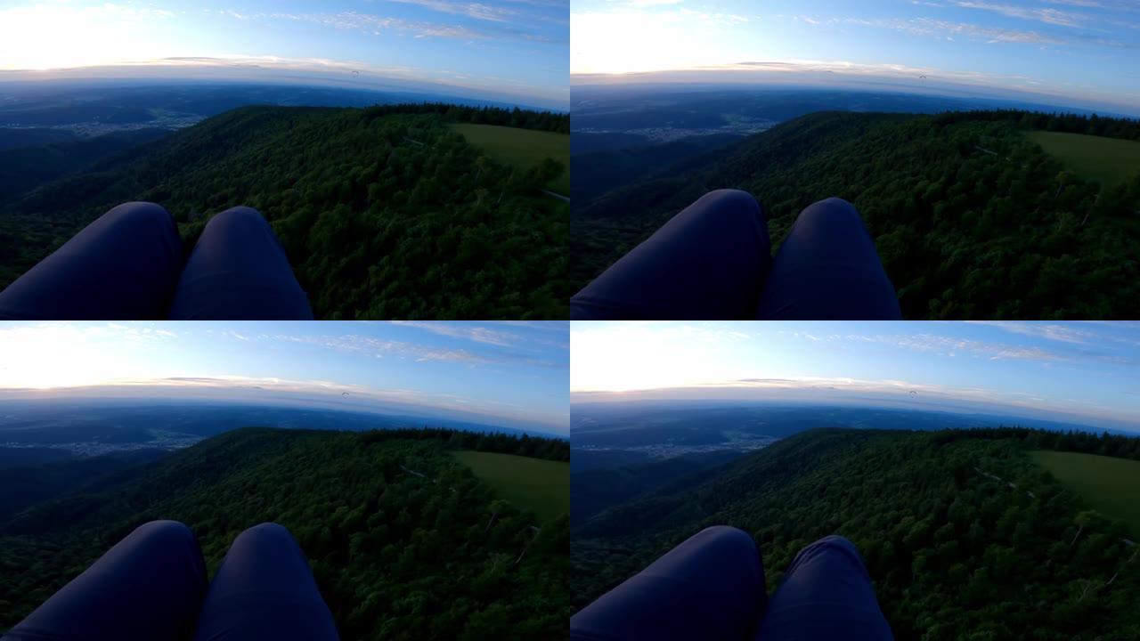 俯视俯冲滑翔伞在黄昏附近的绿色森林上空飞行