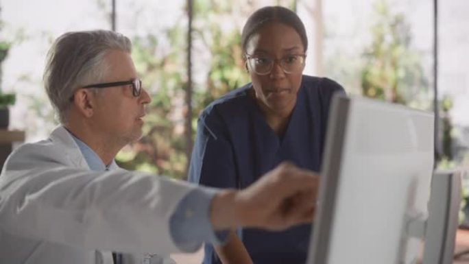 一位美丽的非洲护士和英俊的中年医生在现代医院办公室讲话的肖像: 医生使用台式计算机开药，更新电子健康