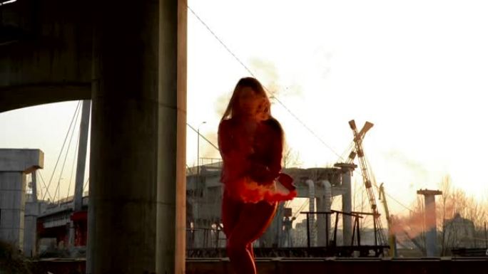 穿着红色服装的美女在废弃桥附近与红色烟雾共舞
