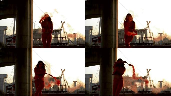 穿着红色服装的美女在废弃桥附近与红色烟雾共舞