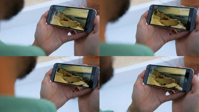 男子拿着手机，在圣托里尼观看跑酷视频，比赛