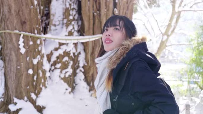 4k亚洲妇女在下雪天看着被雪覆盖的森林山。