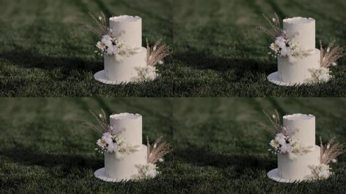 美味的两层婚礼蛋糕。白色婚礼蛋糕的特写，在波西米亚风格的糖衣上有干花的花卉装饰