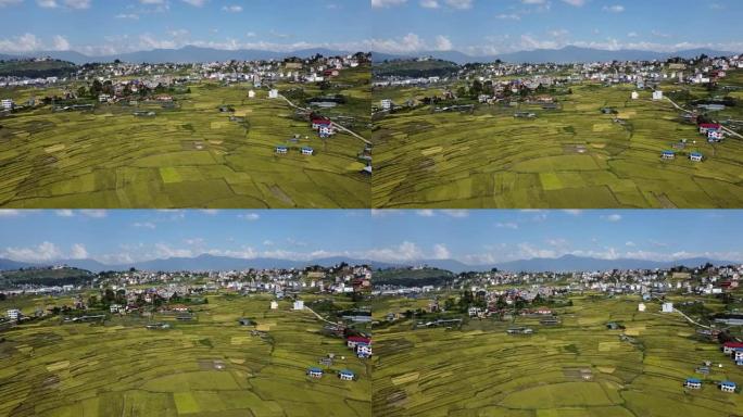 以喜马拉雅山脉为背景的黄色稻田和尼泊尔加德满都市的鸟瞰图。