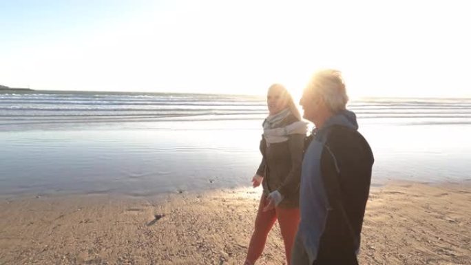 成熟的夫妇沿着空荡荡的海滩散步，有对流