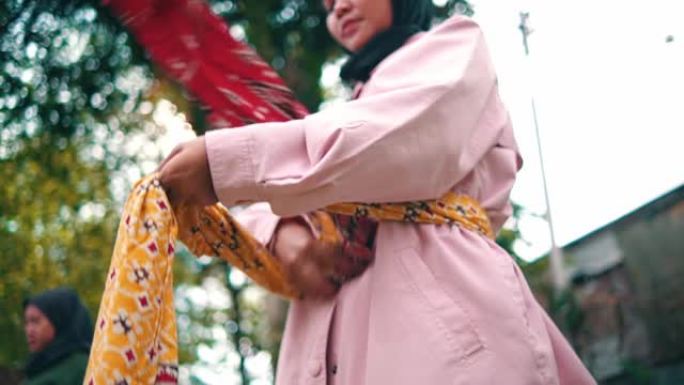 一群穆斯林妇女在花园里练习舞蹈前，在腰间系上一块有图案的布