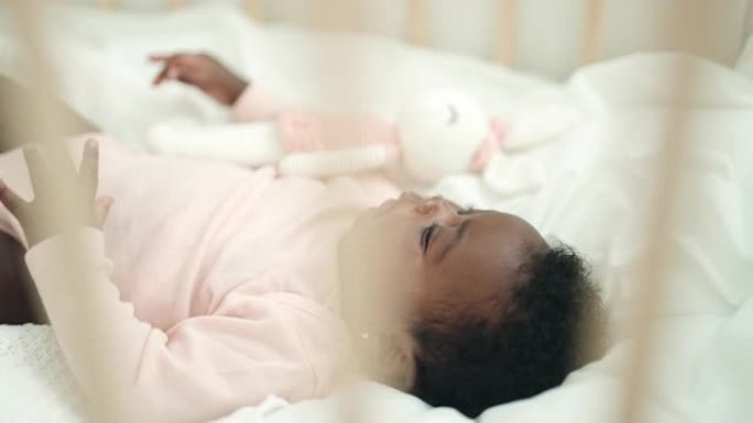 非裔美国人婴儿躺在摇篮上，在卧室里表情轻松