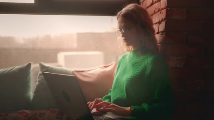 漂亮的金发学生女人在咖啡馆里用笔记本电脑打字，使用免费无线网络，发送信息，上网，自由职业者，坐在窗台