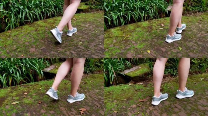 摄像机跟随一个女孩的腿在公园里的一条小路上行走