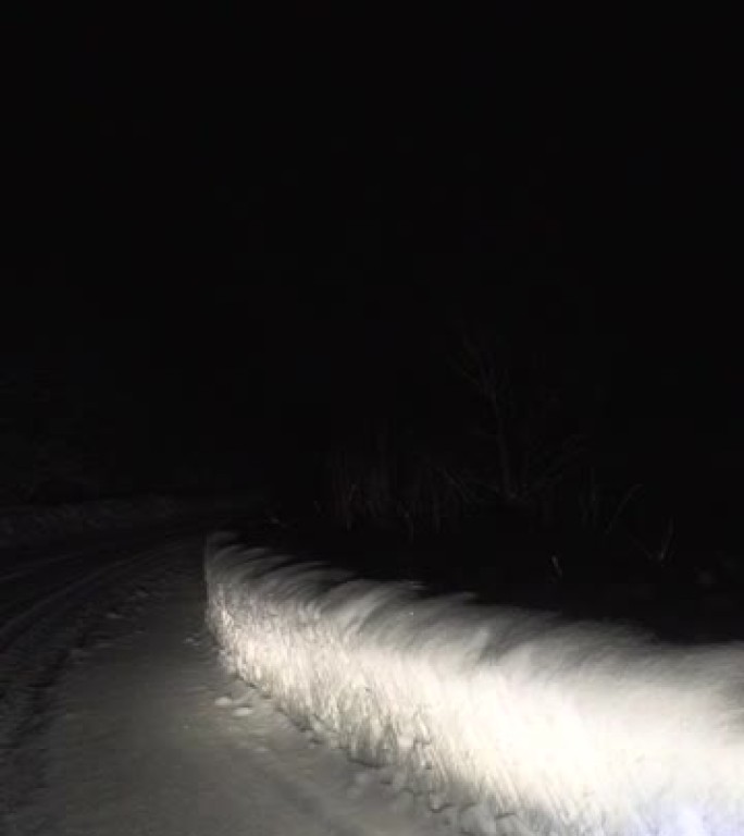 晚上在森林的雪路上开车。掉头