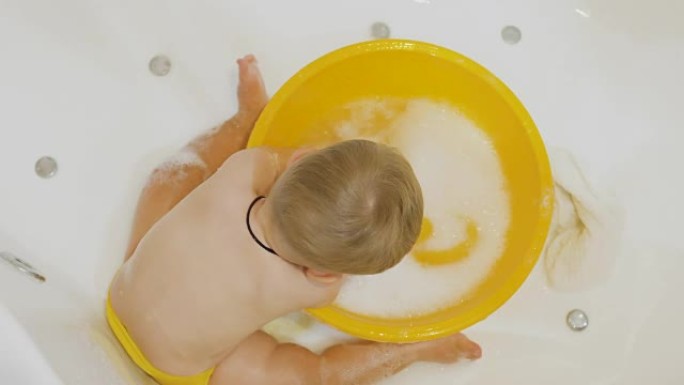 可爱的男孩在浴缸里的盆里泼水