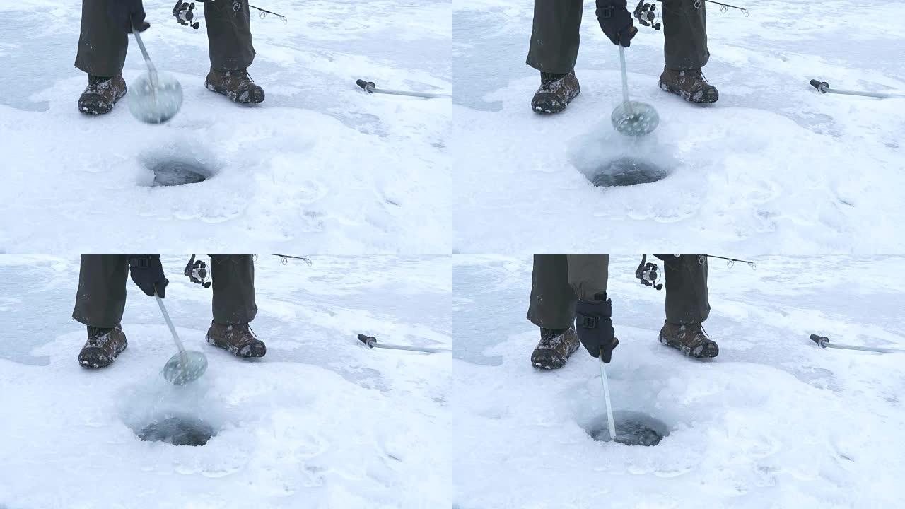 男子在冰冻的湖上挖出冰钓洞