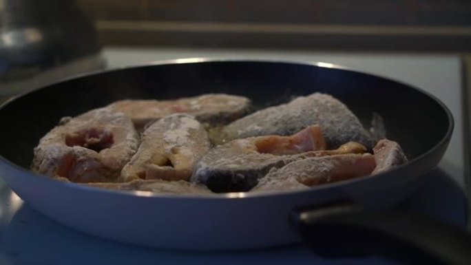 在家用炉灶上的黑色煎锅上烤的新鲜鱼粉。