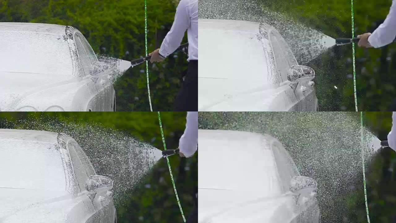 男子使用专业洗车设备在汽车上喷洒泡沫或水
