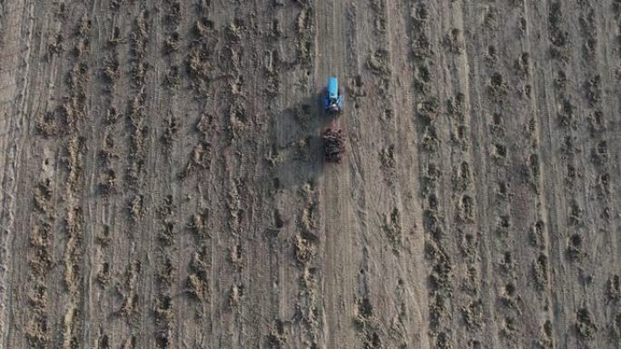 由于欧洲创纪录的干旱，农民在干燥的土壤中驾驶爬行的拖拉机的空中无人机镜头