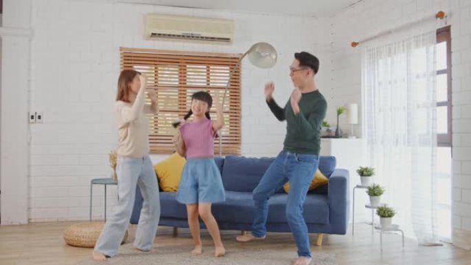 快乐的亚洲家庭母亲父亲和孩子女儿在家里跳舞。