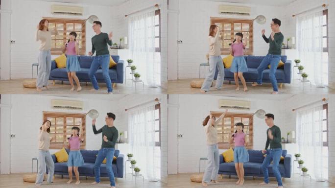 快乐的亚洲家庭母亲父亲和孩子女儿在家里跳舞。