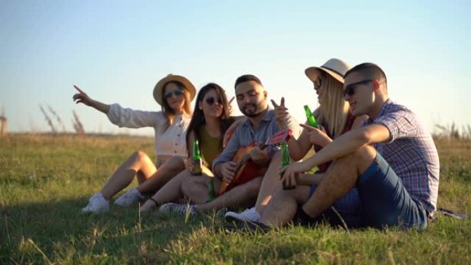 朋友在草地上用吉他和啤酒开小型派对