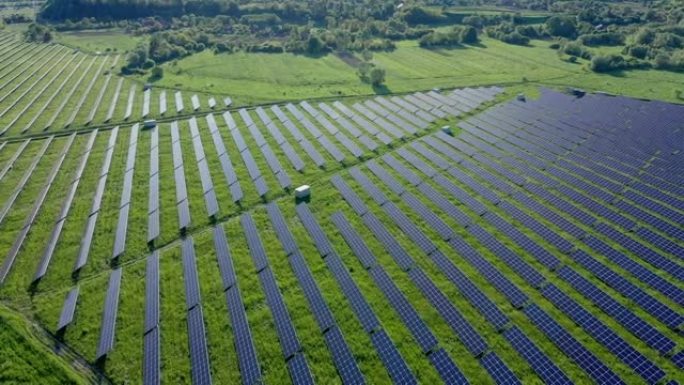 晴天在河附近绿地太阳能电站的鸟瞰图。飞越太阳能农场。太阳能电池板排成一排，用于发电。可再生绿色能源。
