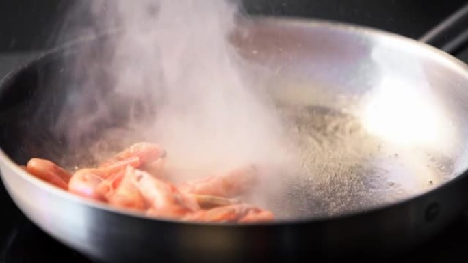 厨师把虾扔在烤架上。大虾在平底锅里煎炸的特写镜头。厨师在热锅上煎皇家虾。宏观海洋食品制备