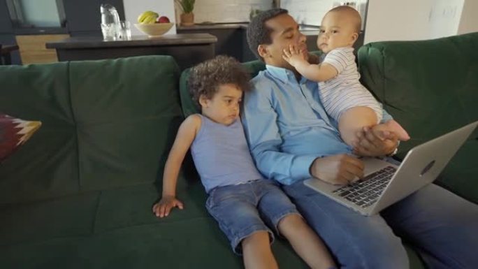 父亲在家处理笔记本电脑时照顾两个儿子