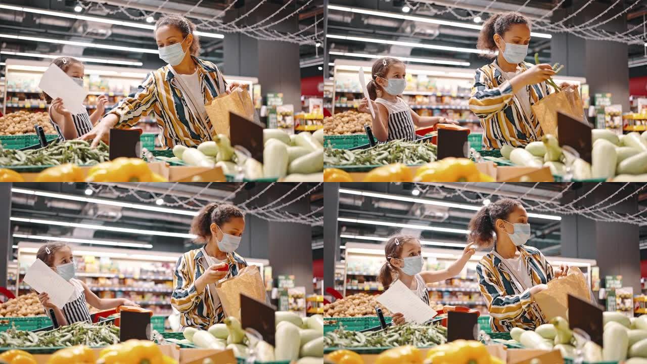 可爱的一家人，一对戴着口罩的母女，在超市买了绿豌豆，放在纸袋里。坐在购物车里拿着购物清单的女孩