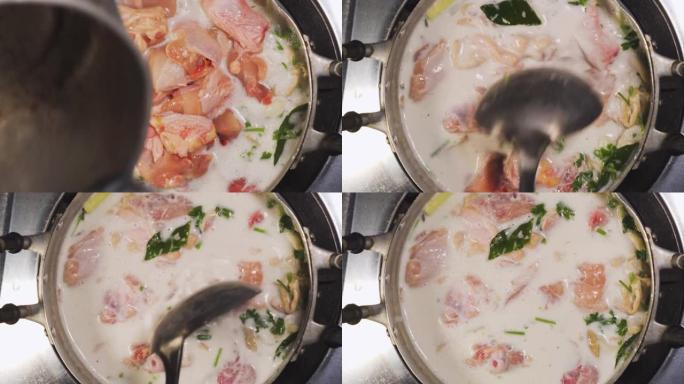 有人放入生鸡肉，搅拌椰奶汤。泰国菜。泰国名菜。顶视图镜头。
