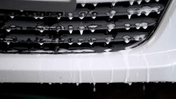 用于消失和清洁的白色泡沫在车身周围流动。化学雪泡沫洗车概念清洁产品。