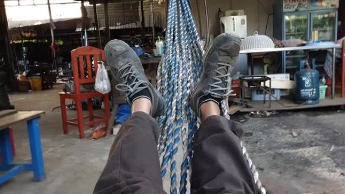 在一家工厂里，一个人的腿躺在吊床上。