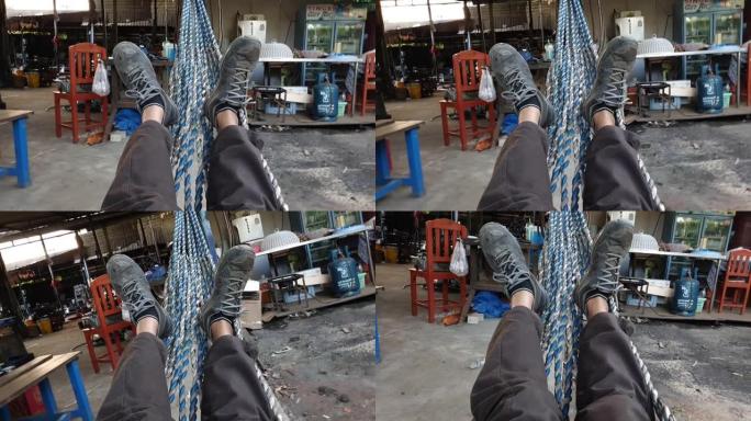 在一家工厂里，一个人的腿躺在吊床上。