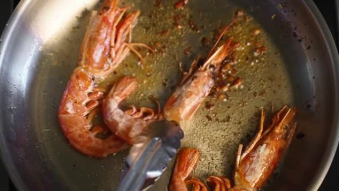 大虾在平底锅里煎炸的特写镜头。厨师在热锅上煎皇家虾。宏观海洋食品制备