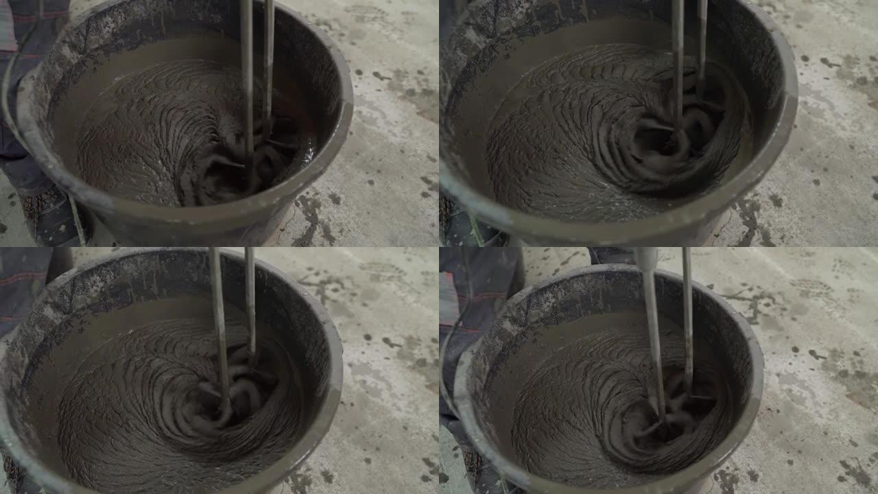 工人将溶液混合在桶中。一名男子使用手动搅拌器将溶液与水桶中的水混合，进行混合，揉捏以修复地板的平整