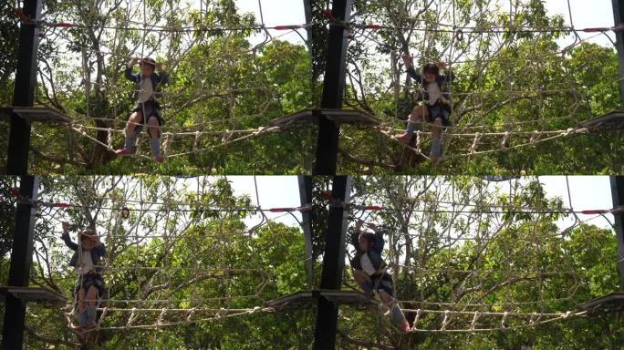 快乐的亚洲小女孩在操场上爬绳网。勇敢冒险的孩子