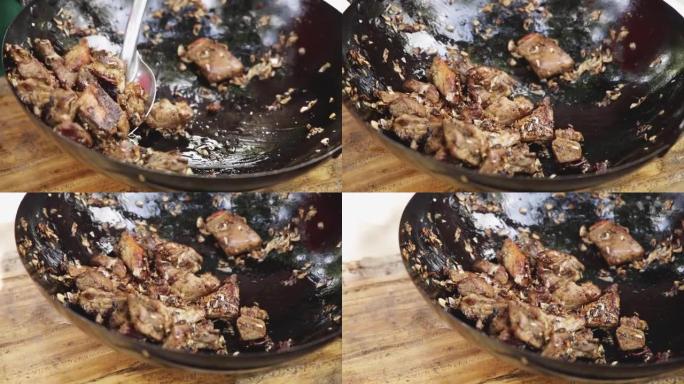 在木菜板上的炒锅里用大蒜和黑胡椒炒鸭肉，用不锈钢刮刀在炒锅里用大蒜炒鸭肉