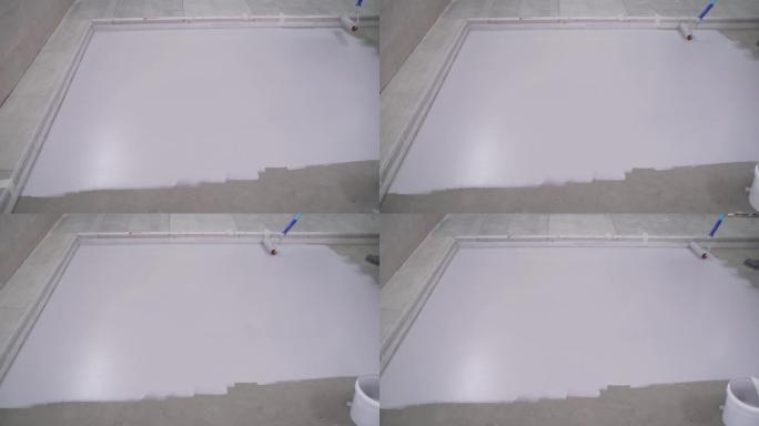 在混凝土地板上应用白色涂料。混凝土地板修整前的底漆。房子里的修理。复制空间。主人用白色油漆粉刷地板