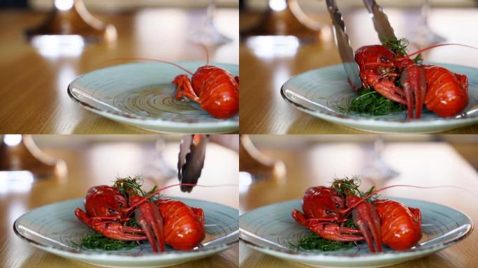 厨师提供豪华的海鲜菜，并用钳子将煮熟的小龙虾从锅里放到盘子里。用大锅蒸龙虾海鲜配莳萝。煮红小龙虾在平