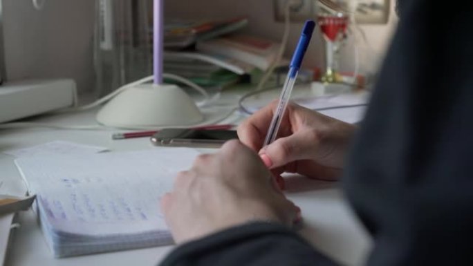 修指甲的年轻少女手握笔，写作业。