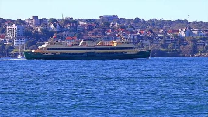 澳大利亚海港的悉尼渡轮在阳光明媚的蓝天上，海湾的绿松石色和城市的高层办公室