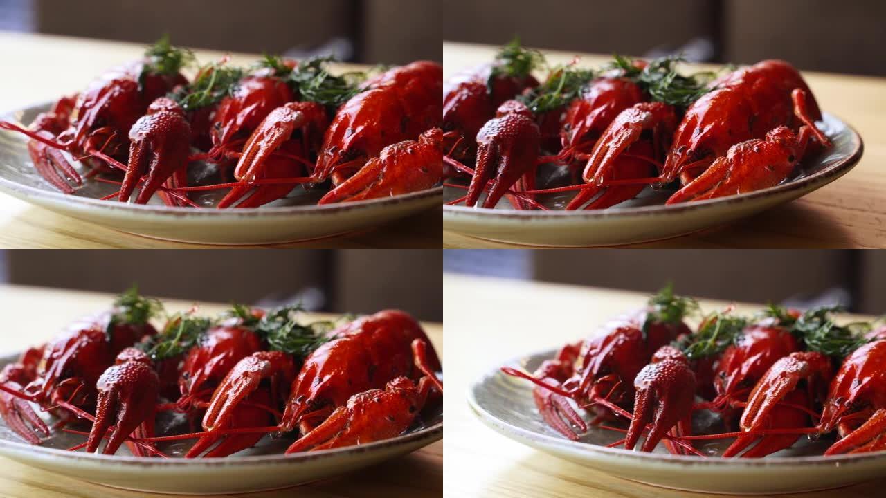 红煮小龙虾放在装有绿色莳萝的盘子里。餐厅的豪华海鲜菜肴。蒸龙虾海鲜放在桌子上。慢动作蒸煮红小龙虾