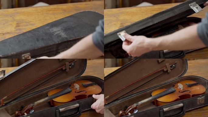 小提琴手用一把老式复古小提琴打开一个箱子。音乐情绪。