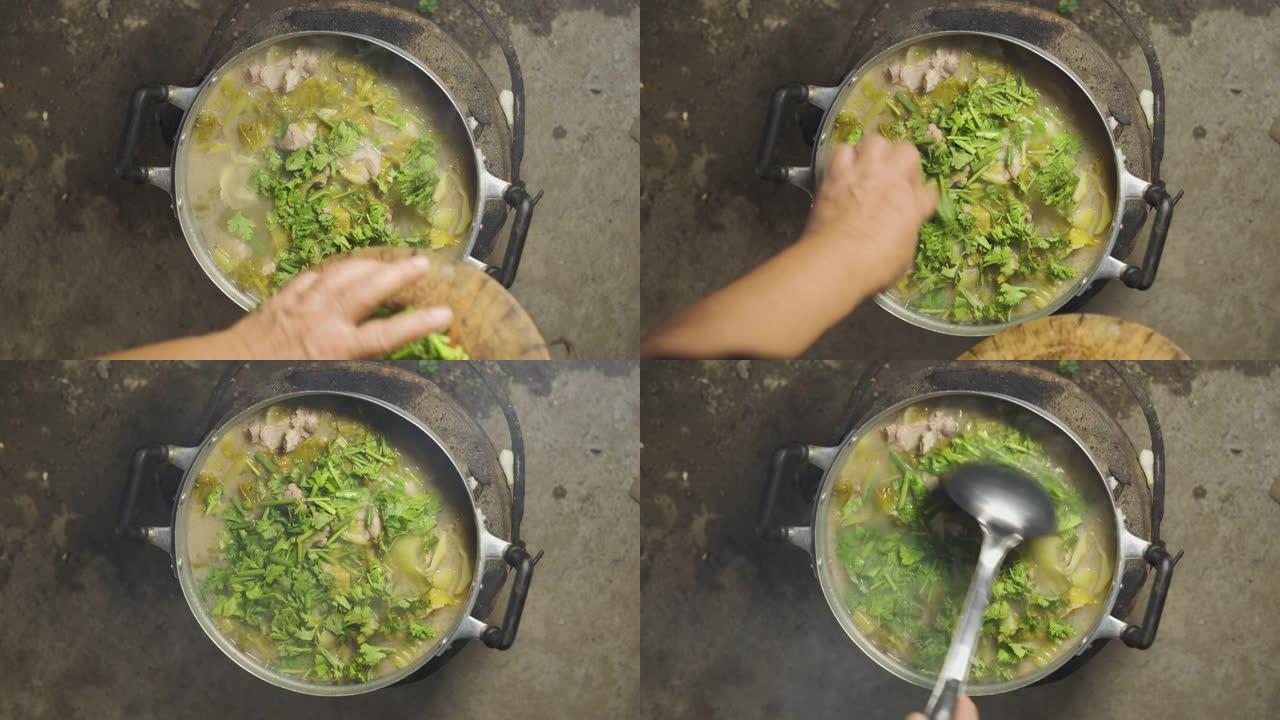 亚洲老太太在装满排骨，酸菜，香菜和葱的汤锅上放了些香菜。最后激动起来。泰国菜菜单。顶视图。