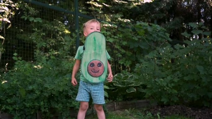 可爱的快乐小男孩，穿着手工鳄梨服装，在后院跳舞。素食，可持续的生活方式，健康的饮食理念。