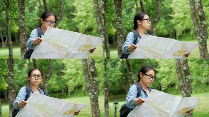 一位女游客，背着背包在户外放松，在森林里的地图上寻找正确的方向。度假概念上的旅行和生活方式。