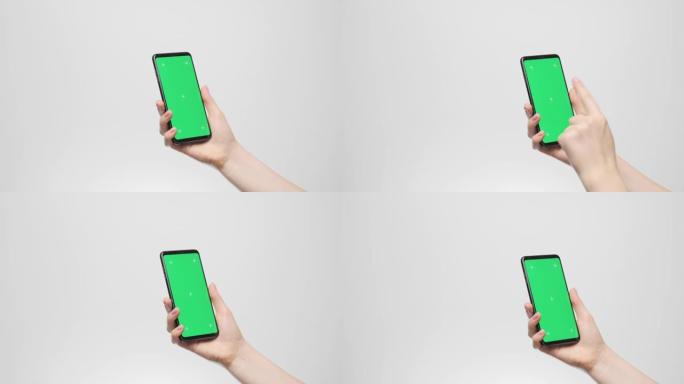 手机的绿色屏幕在一个女人的手在灰色背景上，在屏幕上进行双击。
