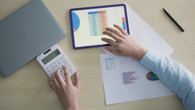 使用计算器计算来汇总或考虑家庭办公室的统计报告以实现业务和财务概念的会计人员的慢动作俯视图场景