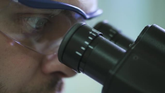 戴着防护眼镜的男科学家通过显微镜观察Spbd的极端特写镜头