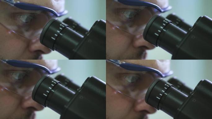 戴着防护眼镜的男科学家通过显微镜观察Spbd的极端特写镜头