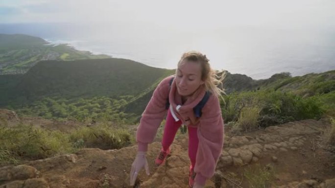 队友帮助徒步旅行者到达顶峰。夫妇在夏威夷徒步旅行，伸出手帮助女性徒步旅行者到达顶峰。援助之手的概念