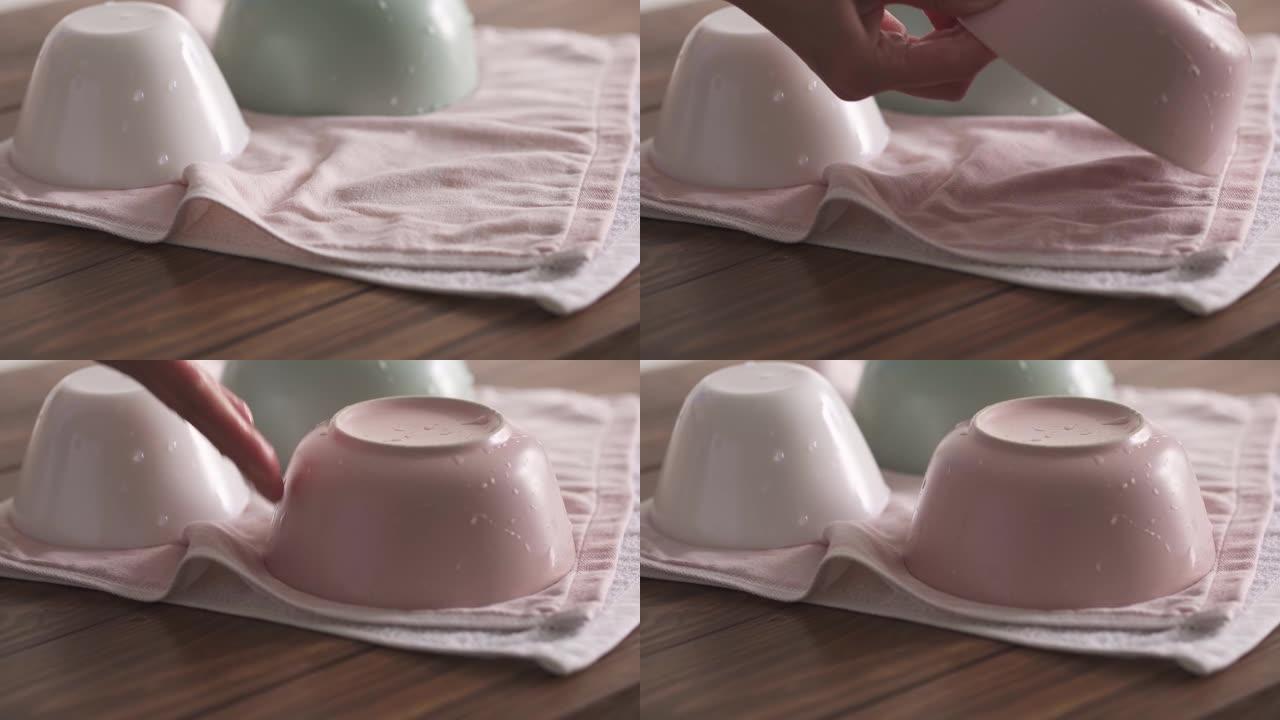 女人的手把湿盘子放在毛巾上。用茶巾清洁碗。优雅柔和的厨房