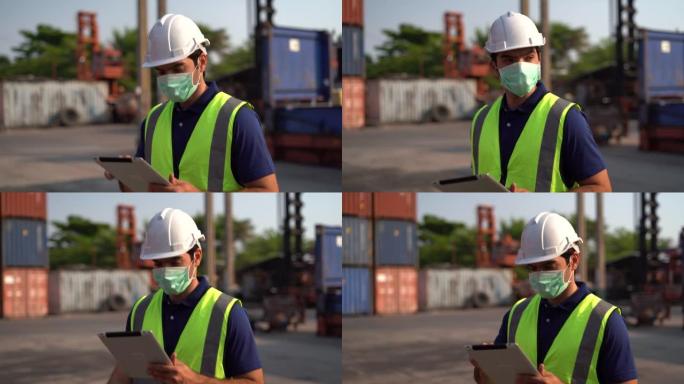 工头戴着口罩，拿着平板电脑步行到货物物流仓库的集装箱清单。冠状病毒或covid 19大流行期间的进出